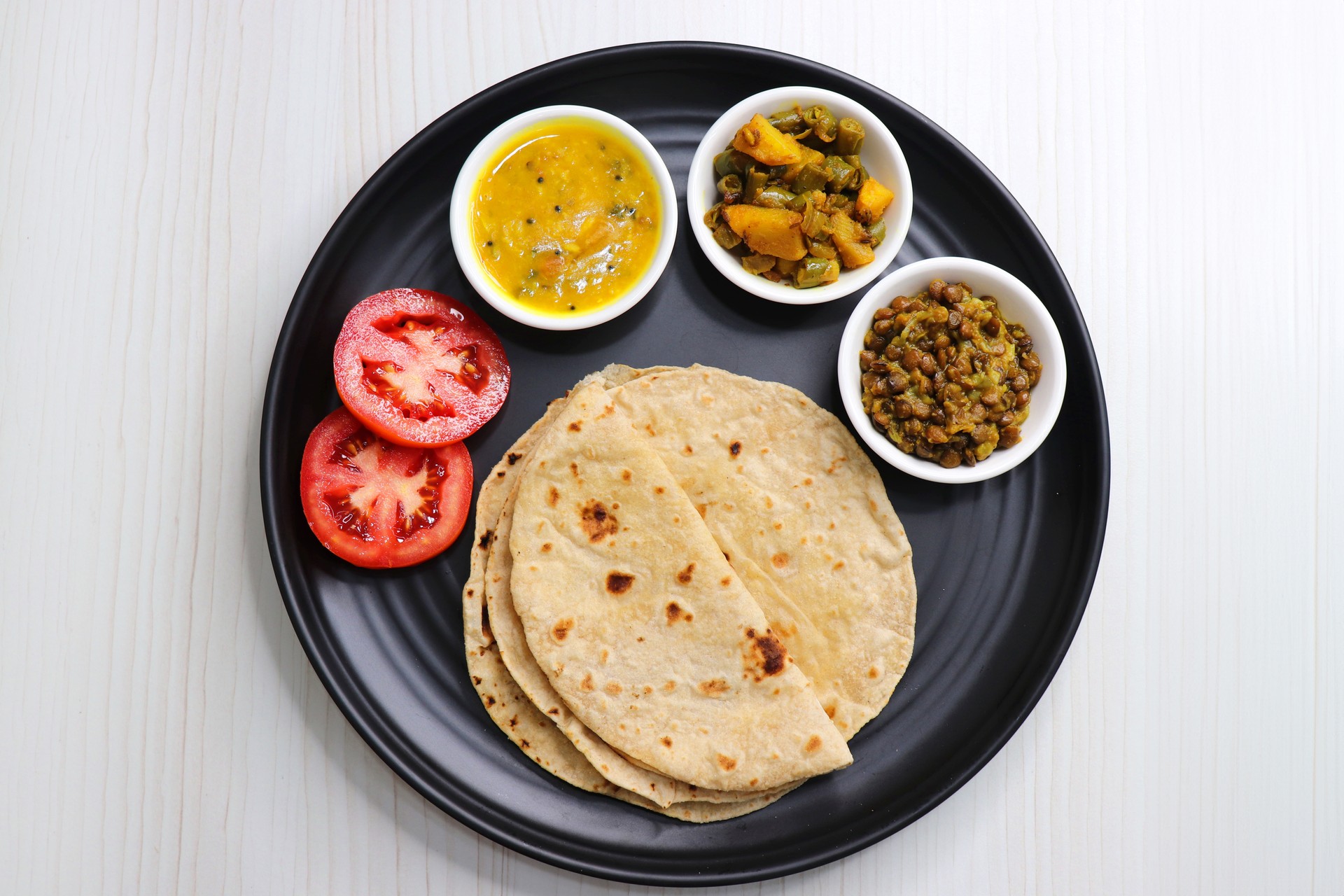 Roti and bhaji. Indian vegetarian Thali or platter includes akhha Masoor sabzi, dal, fansi or beans ki sabji, and chapati. Indian food is served in a plate or thali. Copy Space. healthy Veg Thali.