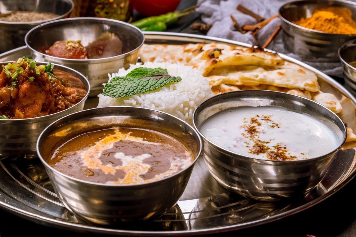 Assorted indian food set on wooden background. Dishes and appetisers of indeed cuisine, rice, lentils, paneer, samosa, spices, masala. Bowls and plates with indian food